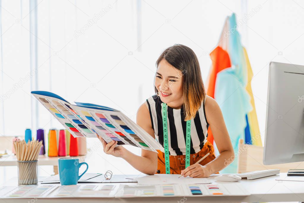 Young Asian designer woman choosing multicolor chart and writing noted at workplace, small business startup, Business owner entrepreneur, modern freelance job lifestyle concept. asean people