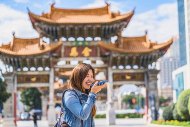 Asyalı gezgin kadın Jinbi Meydanı, Kunming, Çin, seyahat ve turizm, ünlü yer ve simge konsepti üzerinden seyahat ederken çeviri yapmak için akıllı cep telefonu kullanıyordu.