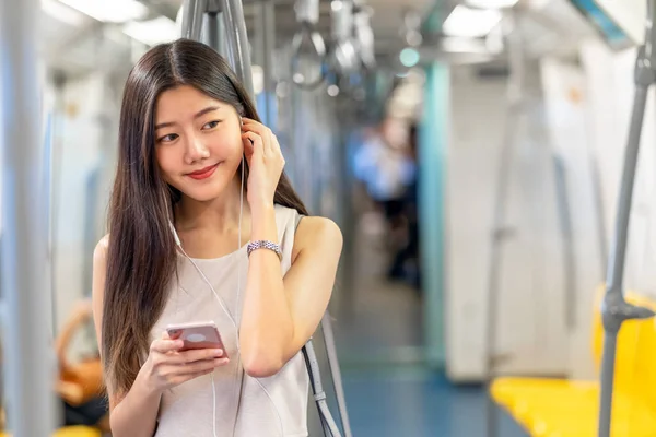 Νεαρή Ασιατική Γυναίκα Επιβατών Ακούγοντας Μουσική Μέσω Έξυπνο Κινητό Τηλέφωνο — Φωτογραφία Αρχείου