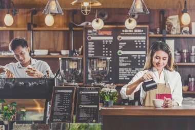 Kafede müşteri siparişi vermek için Asyalı barista kahve, espresso ya da cappuccino hazırlıyor, barmen süt dolduruyor, küçük işletme sahibi ve restoran ve kahve dükkanında işe başlıyor.