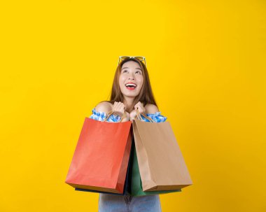 Çekici Asyalı gülümseyen genç bir kadın izole edilmiş sarı arka planda alışveriş çantası taşıyor, fotokopi alanı ve stüdyo, siyah cuma sezonu satış konsepti.