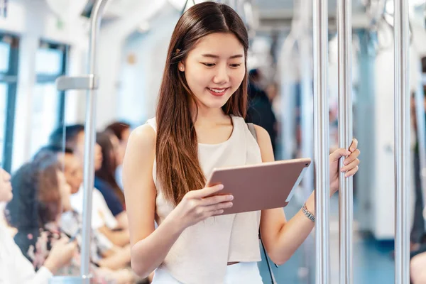 大都市 日本語 中国語 韓国語の生活や日常生活 通勤や交通の概念で旅行するときに地下鉄の電車の中で技術タブレットを介してマルチメディアプレーヤーを使用して若いアジアの女性の乗客 — ストック写真