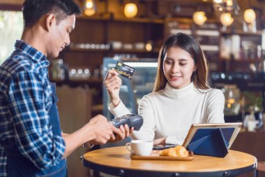 Asyalı müşteri kadın kredi kartıyla Asya 'daki Kafe' deki küçük kahve dükkanı sahibine, küçük işletme sahibine ve kahve dükkanı konseptine ulaşılamayan bir teknoloji ile ödeme yapıyor.