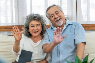 Asyalı çift, büyük anne ve baba, cep telefonuyla yapılan video telefon görüşmesi, çok yaşa ve yaşlılar topluluğu, sıcak aile ve mutluluk kavramı aracılığıyla mutlu bir şekilde selamlıyorlar.