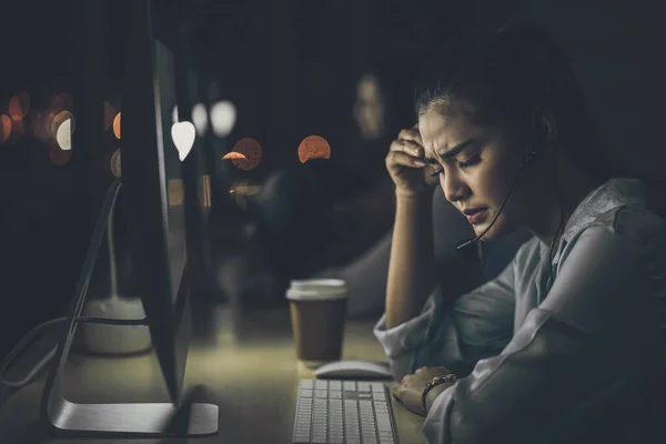 アジアのビジネス女性は オフィス カスタマーサービス コールセンター部門 ハードワーカー ストレスや頭痛 低光環境で彼女の技術コンピュータで遅く働いています — ストック写真