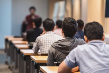 Toplantı odasında ya da konferans salonundaki Asyalı konuşmacıyı dinleyen seyircinin dikiz görüntüsü, seminer işi ve eğitim konsepti