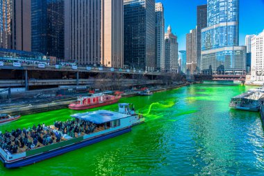 Chicago, Illinois, Usa 'daki yeşil renkli nehri boyayan Şikago nehri çevresindeki Aziz Patrick gününde Chicago' daki bina ve şehir manzarası taçlandırılmış İrlandalıları ve Amerikan halkını kutluyor..