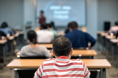 Toplantı odasında ya da konferans salonundaki Asyalı konuşmacıyı dinleyen seyircinin dikiz görüntüsü, seminer işi ve eğitim konsepti