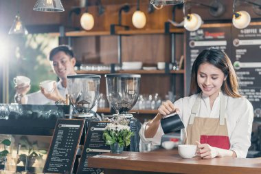 Kafede müşteri siparişi vermek için Asyalı barista kahve, espresso ya da cappuccino hazırlıyor, barmen süt dolduruyor, küçük işletme sahibi ve restoran ve kahve dükkanında işe başlıyor.