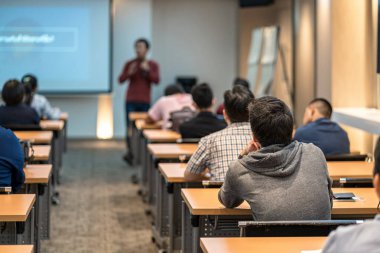 Toplantı odasında ya da konferans salonundaki Asyalı konuşmacıyı dinleyen seyircinin dikiz görüntüsü, seminer işi ve eğitim konsepti