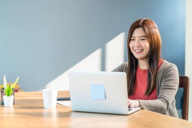 Asyalı iş kadını teknolojik dizüstü bilgisayar kullanıyor ve evden modern evde çalışıyor, serbest ve girişimci, yaratıcı tasarım ve blog yazarı, sosyal mesafe ve kişisel sorumluluk kavramı