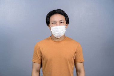 Mavi arka planda yüz maskesi takan Asyalı erkek portresi; Coronavirüs salgını; covid19 salgını; sosyal uzaklık ve sorumluluk; sağlık ve virüs konseptine karşı koruma
