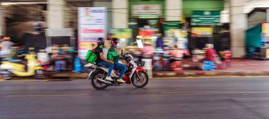 BANGKOK, THAILAND - Nisan 2020: 17 Nisan 2020, Bangkok, Tayland 'da motorsikletle yiyecek dağıtımına giden Kap Gıda Motorcularının hareket bulanıklığı.