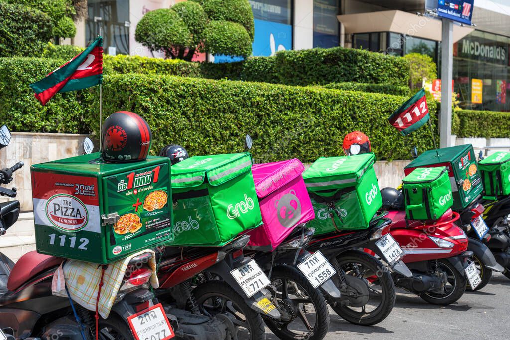 BANGKOK, THAILAND - APRIL 2020 : Grab Food Logo on Food boxes on the motorcycles between food panda at Food delivery service point on April 17, 2020, Bangkok, Thailand,Covid19 outbreak delivery services