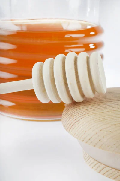 Container of honey with a stick — Stock Photo, Image