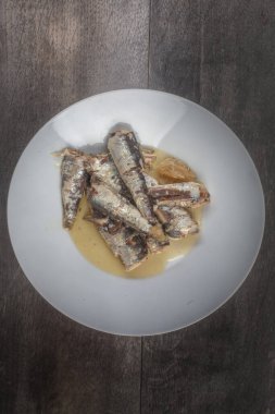 Stüdyoda sardalyaların beyaz tabaka merkezindeki fotoğrafı ahşap arka plandaki üst kompozisyonda.