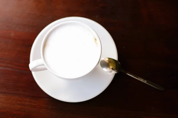 Uma chávena de café na mesa de madeira. Cappuccino. Luzes no fundo. Vista superior . — Fotografia de Stock