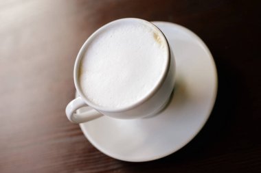 Tahta masada bir fincan kahve. Işıklar arka planda. Ön görünüm.