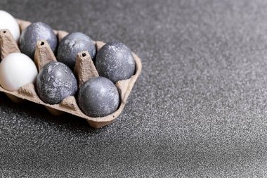 Mermer taş efektli yumurtalar gri parlak arka planda doğal boya kartonuyla boyanmış.
