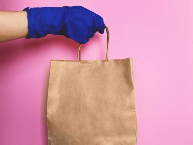 Tüketici paketi ürünü. Teslimat. Eldivenin içinde saplı kahverengi bir el işi paketi var. Logo için boşluk.