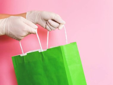 Tüketici paketi ürünü. Teslimat. Eldivenin içinde saplı yeşil bir el işi paketi var. Logo için boşluk.