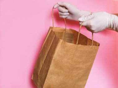 Tüketici paketi ürünü. Teslimat. Eldivenin içinde saplı kahverengi bir el işi paketi var. Logo için boşluk.