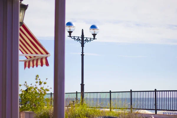 Deniz kenarındaki kafeteryada açık hava masaları ve panoramik manzarası var. Sokak lambası. Biberiye Çalılığı