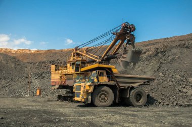 Taş ocağı Ekskavatör Damper demir cevheri ile yükler.