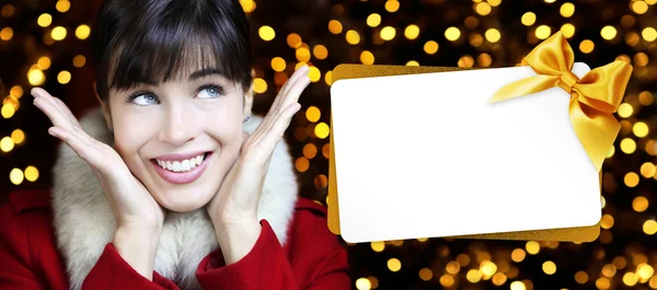 Mujer con tarjeta de regalo de Navidad en fondo de luces doradas —  Fotos de Stock