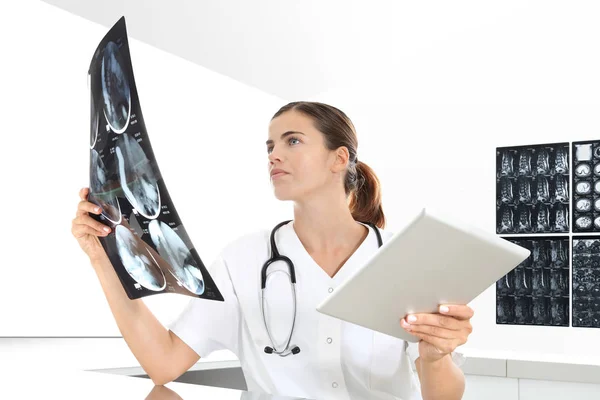 Radióloga mujer que revisa rayos X, con tableta, atención médica — Foto de Stock