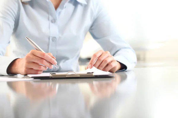 Woman hands writing on clipboard with a pen, isolated on desk Royalty Free Stock Photos
