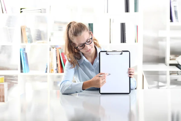 Mains de femme montrant presse-papiers avec un stylo, assis dans le bureau — Photo