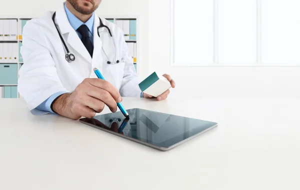 El médico que usa la tableta en el escritorio prescribe el medicamento —  Fotos de Stock
