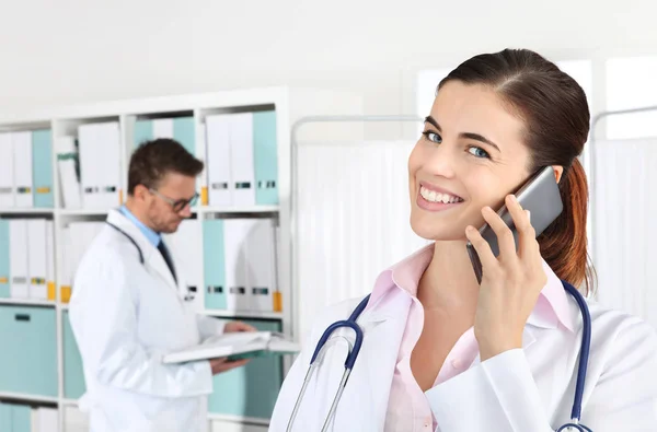 Dokter glimlachend op de telefoon, concept van medische boeken — Stockfoto