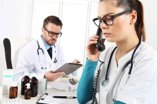 Médico con la tableta y la enfermera al teléfono en el consultorio médico — Foto de Stock