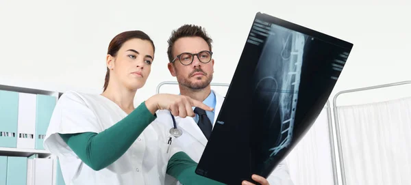 Médicos mirando rayos X en el consultorio médico, señalando con el dedo — Foto de Stock