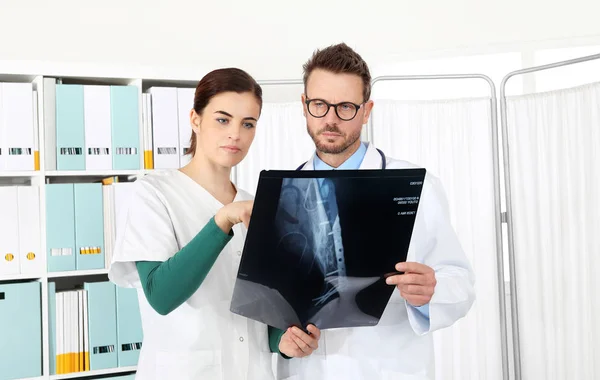 Médicos mirando rayos X en el consultorio médico, señalando con el dedo —  Fotos de Stock