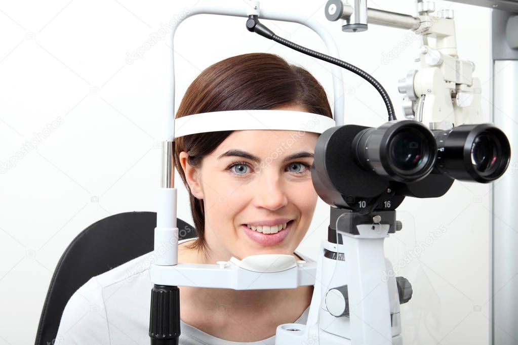 smiling woman doing eyesight measurement with optical slit lamp