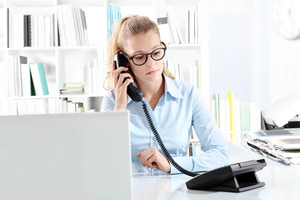 Mulher falando no telefone no escritório na mesa na frente do computador — Fotografia de Stock