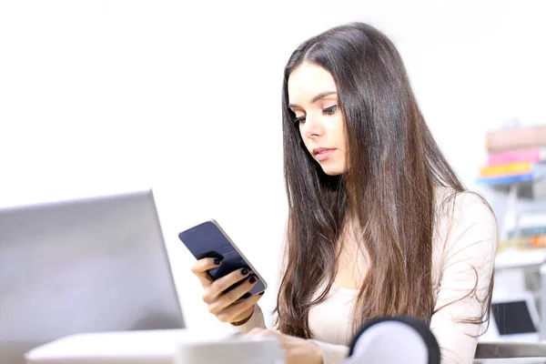 Mensaje de texto de mujer joven, utilizando el teléfono celular en el escritorio —  Fotos de Stock