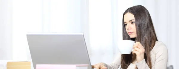 Молодая женщина с компьютером и чашкой в руке — стоковое фото