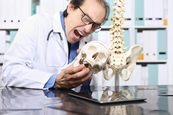 Médico loco con cráneo en la oficina, concepto loco — Foto de Stock