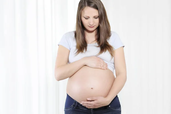 Jovem bela mulher grávida tocando sua barriga com as mãos — Fotografia de Stock