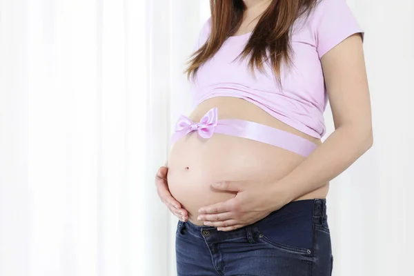 孕妇的肚子，孤立的白色背景上的粉红蝴蝶结 — 图库照片