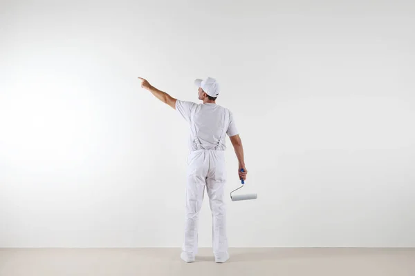 Bakifrån av målare man pekar med fingret tomma väggen, wi — Stockfoto