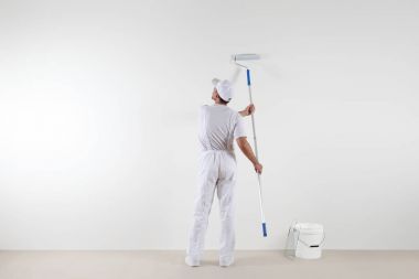 Boya sopa ile boş duvara bakarak ressam adam arkadan görünüş