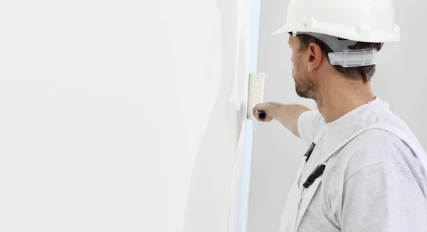 Pintor homem no trabalho com um rolo de pintura, conceito de pintura de parede — Fotografia de Stock