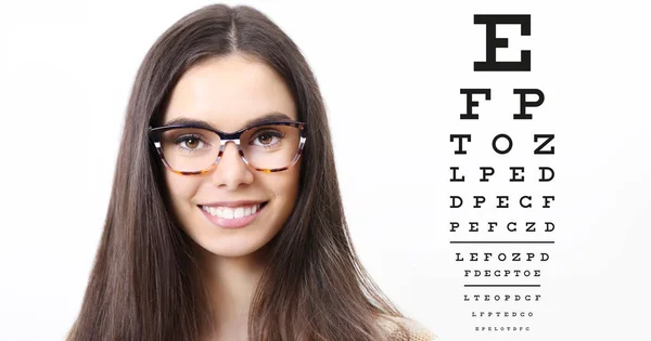 Sonrisa cara femenina con gafas en el fondo de la tabla de prueba de la vista, el examen de los ojos oftalmología concepto —  Fotos de Stock