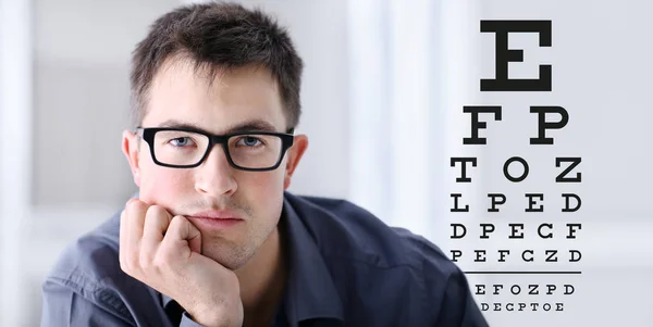 male face with spectacles on eyesight test chart background, eye