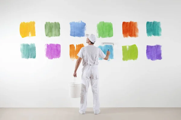 Rear view of painter man who make and chooses from various color — Stock Photo, Image